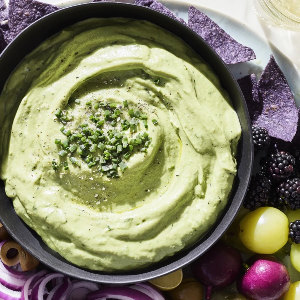 Witch's Brew Cauldron, a Halloween appetizer: creamy green dip, surrounded by dark, spooky ingredients.