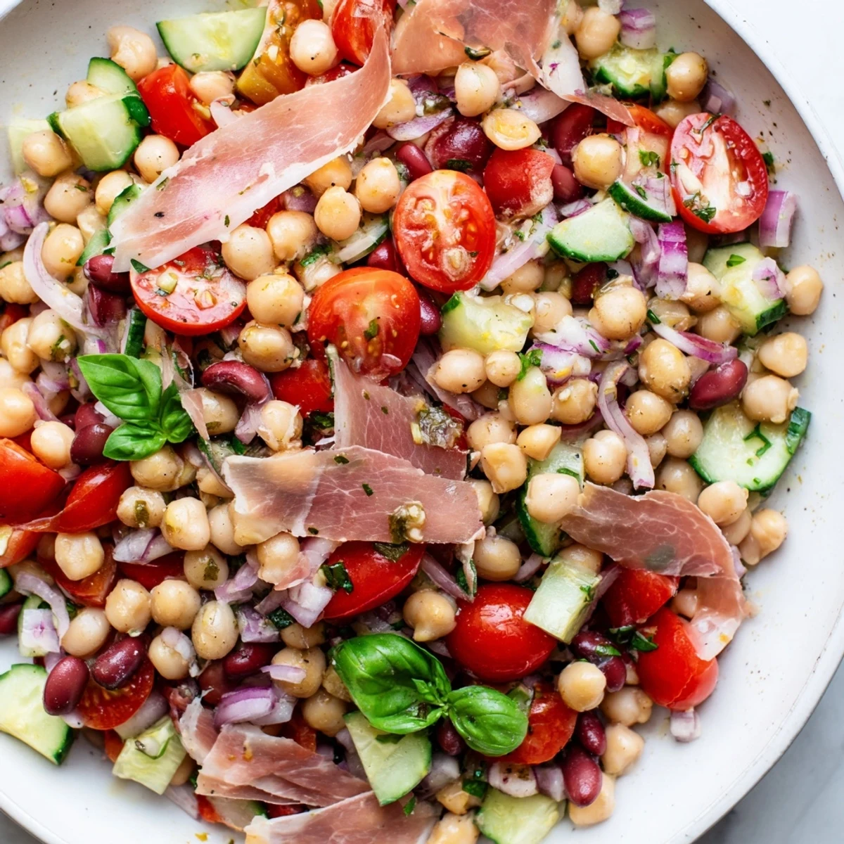 Close-up of a flavorful dense bean salad with prosciutto, featuring a zesty vinaigrette dressing.