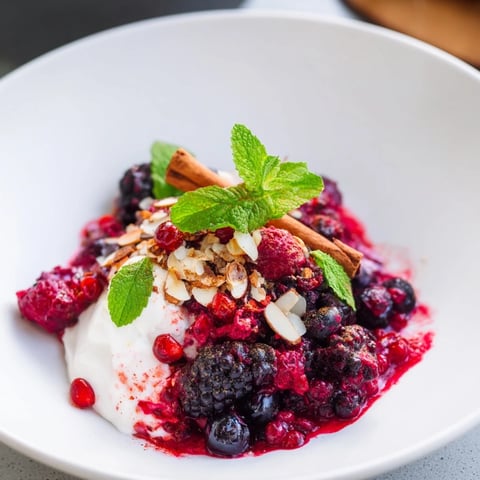 Warm German spiced berry compote cascading over creamy vanilla yogurt, a beautiful dessert.