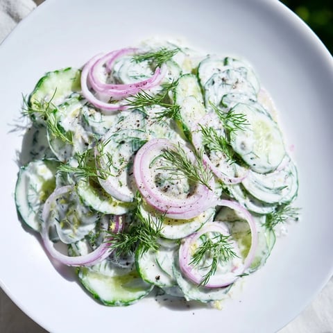 Erfrischender kalter Gurken-Dill-Salat mit cremiger Jogurt-Kräuter-Soße, garniert mit frischem Dill.