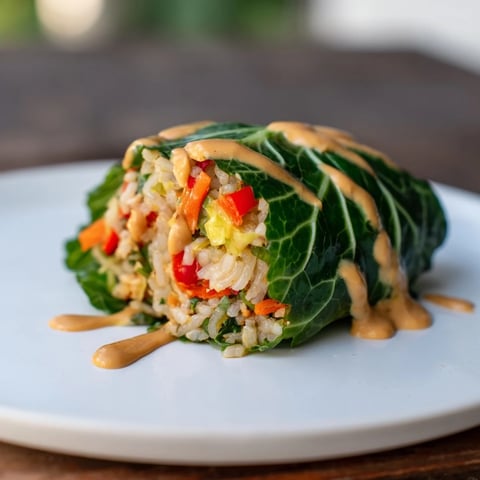 Savoy Cabbage Rolls with Thai Peanut Sauce, a delicious vegetarian main course, served hot.