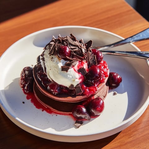 Fluffy and delicious Black Forest Pancake Minis stacked high with cherries, cream, and chocolate, ready to eat.