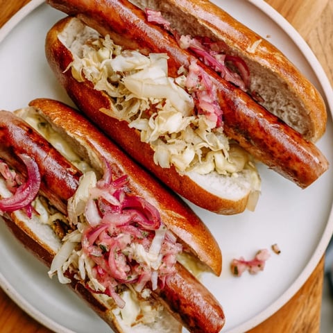 Mini Bratwurst Sliders with grilled bratwurst, mustard, and sauerkraut, a savory snack.
