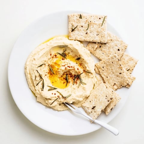 Golden-brown holiday crackers with rosemary and creamy hummus, a perfect appetizer duo.