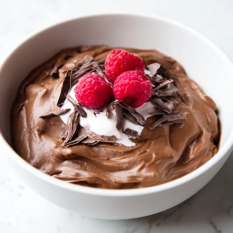 Creamy avocado chocolate pudding, swirled and topped with fresh berries, a decadent vegan dessert.