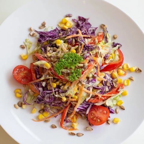 A vibrant Rainbow Salad, showcasing colorful, fresh vegetables drizzled with creamy tahini dressing.