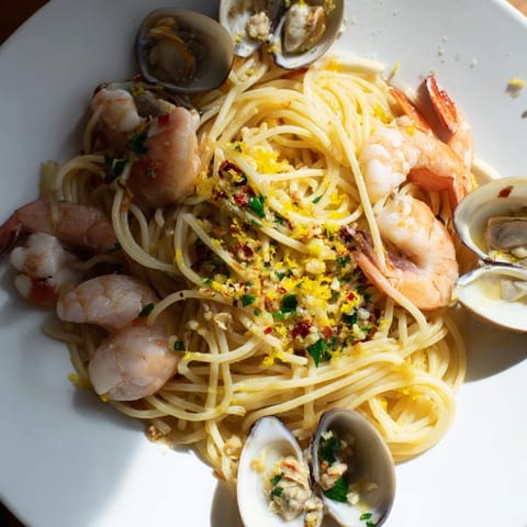 Freshly cooked Seafood Pasta Aglio e Olio with glistening shrimp and clams, ready for dinner.
