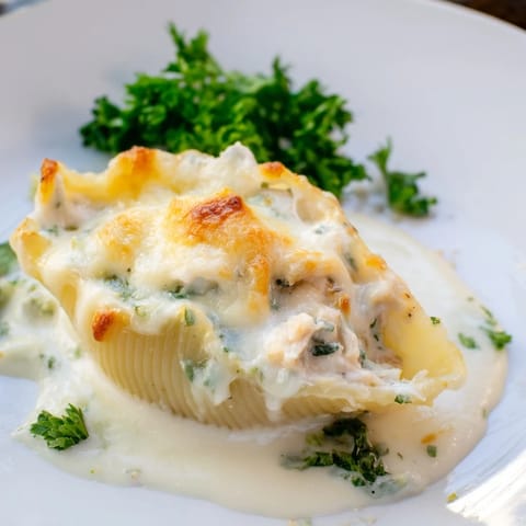 Tender jumbo pasta shells filled with creamy chicken Alfredo, served bubbling hot with a side of garlic bread.