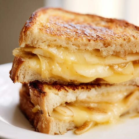 Golden-brown Smoked Gouda & Apple Grilled Cheese slices on a plate, with melted cheese stretching between sourdough bread and crisp apple layers.  