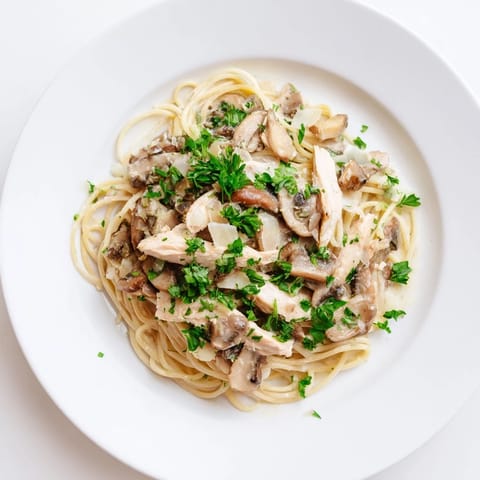 Ein Teller Creamy Mushroom Chicken Spaghettini mit goldbraunen Hähnchenstreifen, Pilzen und frischer Petersilie garniert.