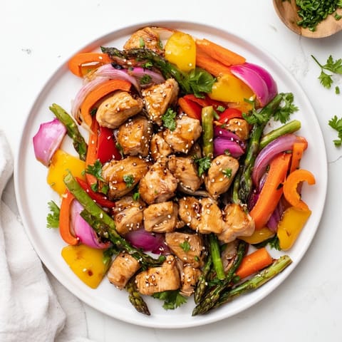 Röstige Honey Garlic Chicken mit bunten Frühlingsgemüse auf einem Backblech, garniert mit frischer Petersilie und Sesam, serviert auf Reis.