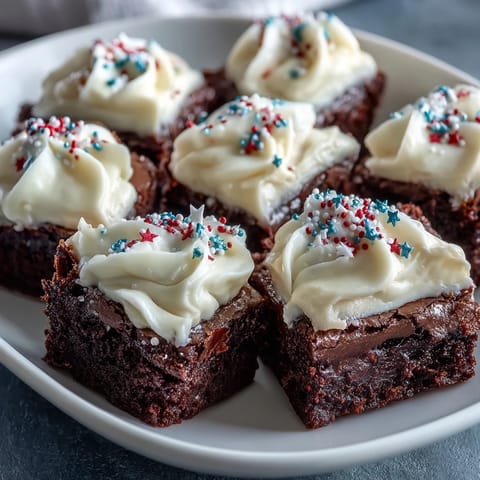 Fudgy 4th of July Firecracker Brownie Bites mit cremiger Glasur und festlichen Streuseln, perfekt für den Unabhängigkeitstag.