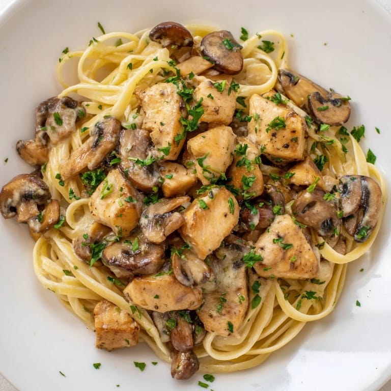A steaming bowl of creamy mushroom chicken pasta, rich sauce coating the noodles.
