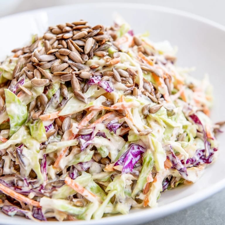 A close-up view of a fresh crunchy coleslaw salad, showcasing vibrant vegetables and sunflower seeds.